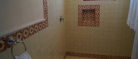 A bathroom with a tiled floor, a toilet, a sink, a towel rack, and a window.
