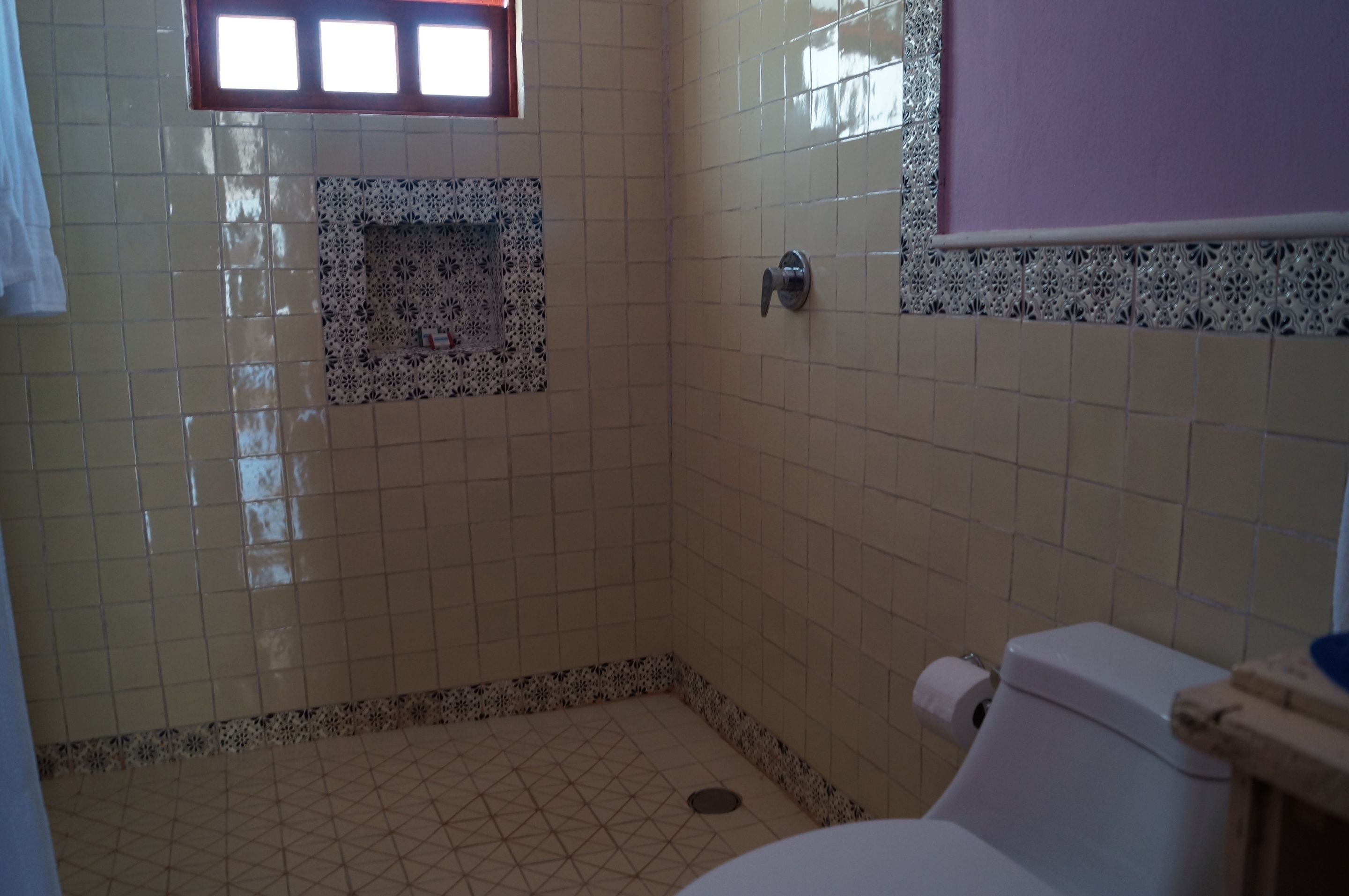 A bathroom with tiled walls, a toilet, and a window.