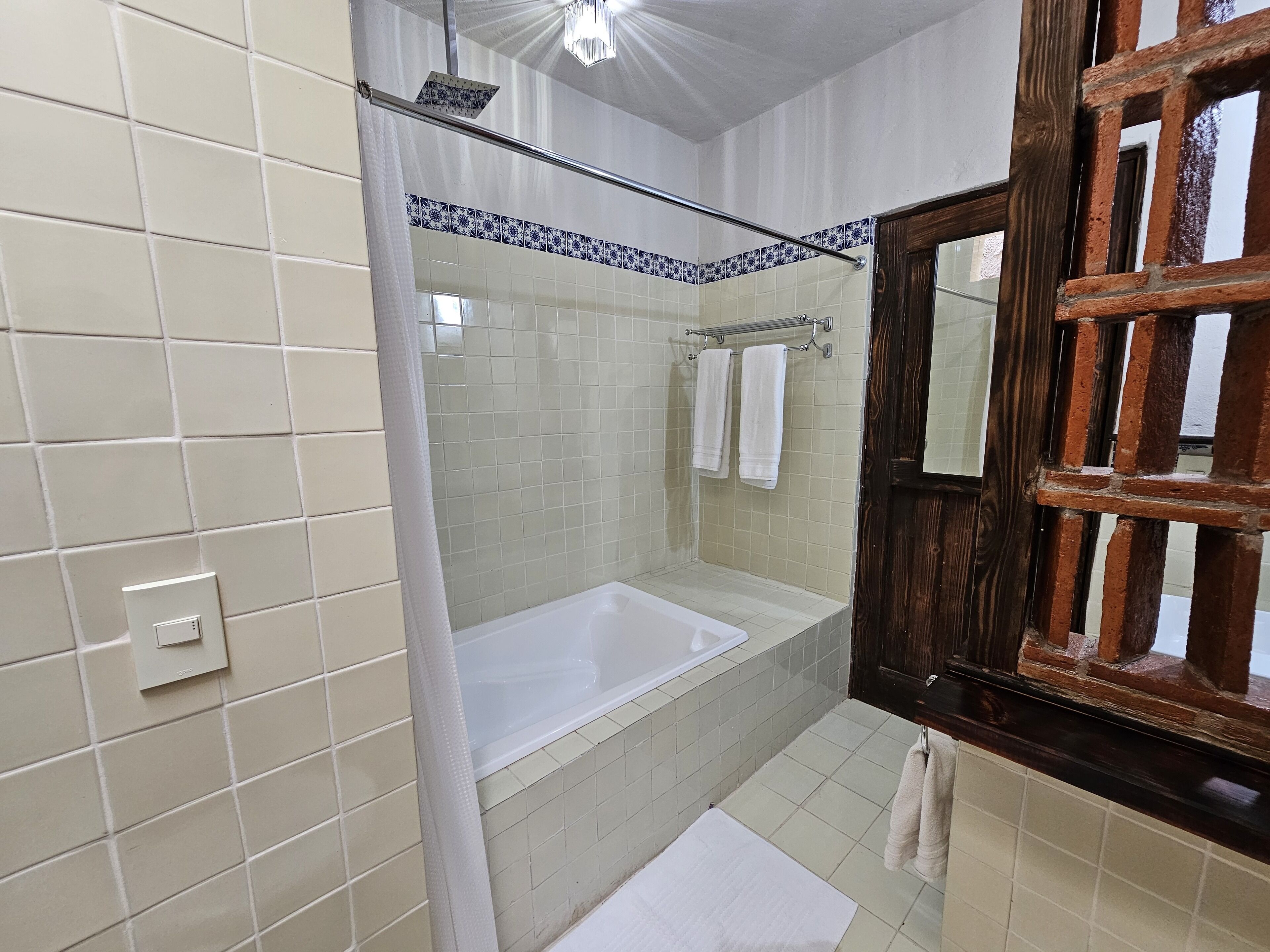 A bathroom with a bathtub, a shower, and a wooden-framed mirror.