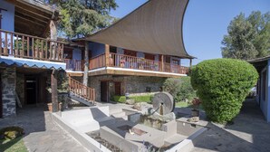 A stone building with a wooden balcony, a stone fountain, and a well-maintained garden.