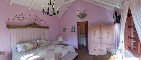 A bedroom with a bed, bench, dresser, and a table with a lamp.