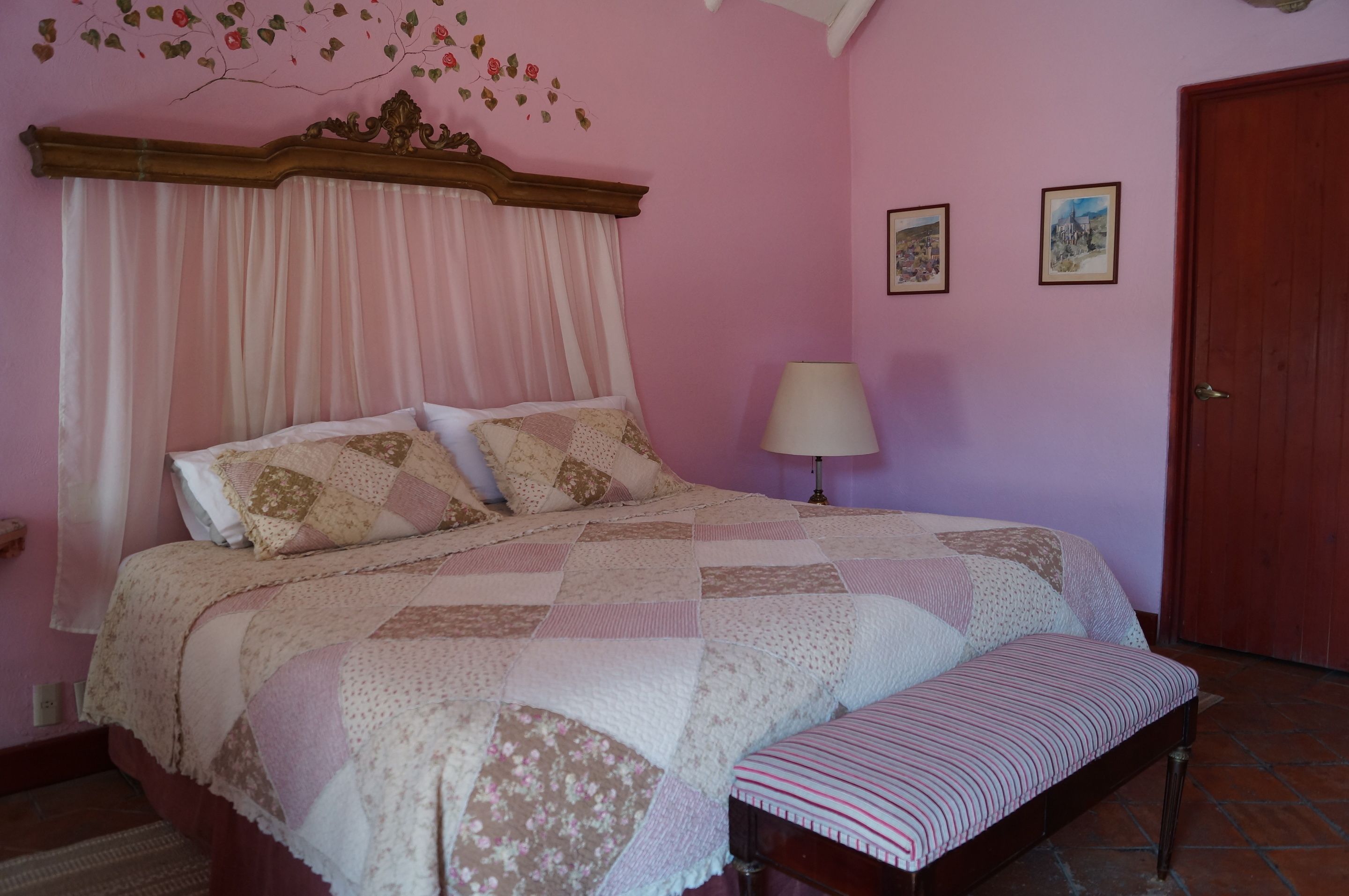 A bedroom with a large bed, a bedside table, a lamp, and a door.