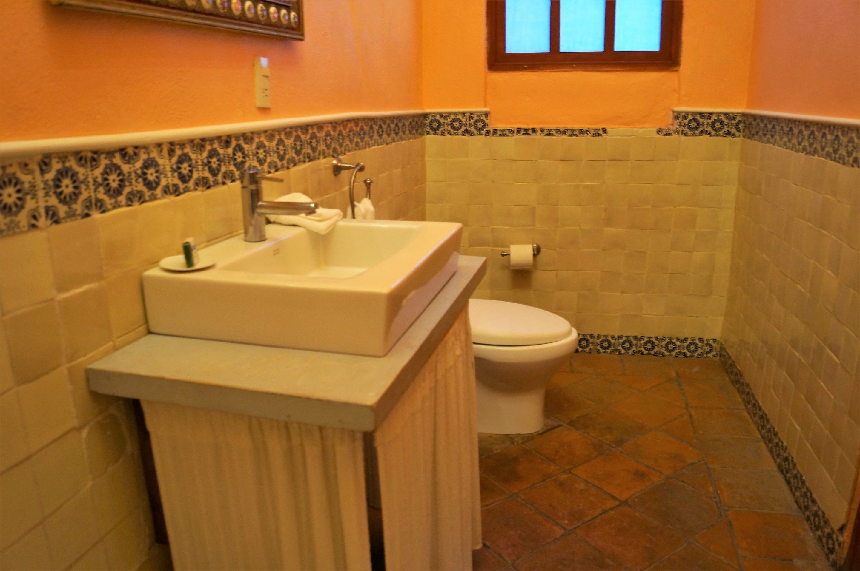 A bathroom with a white sink, a toilet, and patterned tiles on the walls and floor.