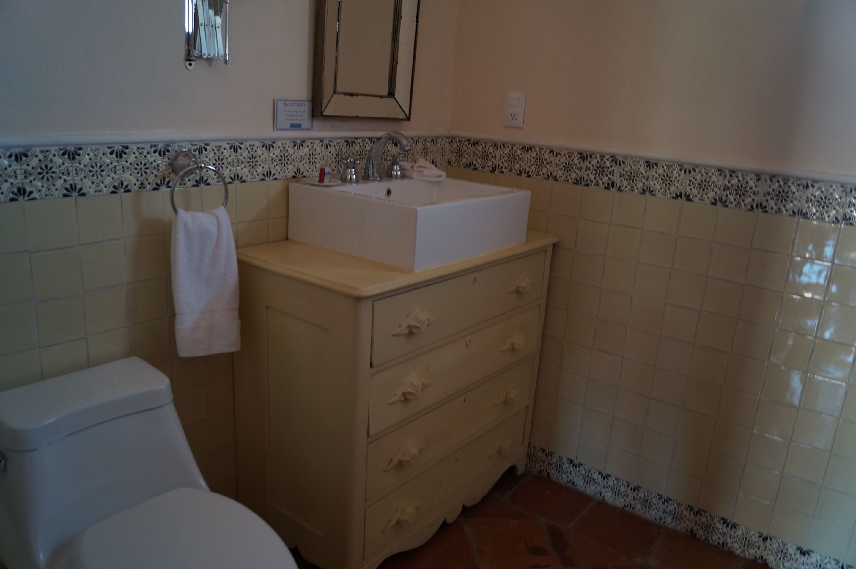 A bathroom with a white sink, beige vanity, and a toilet.