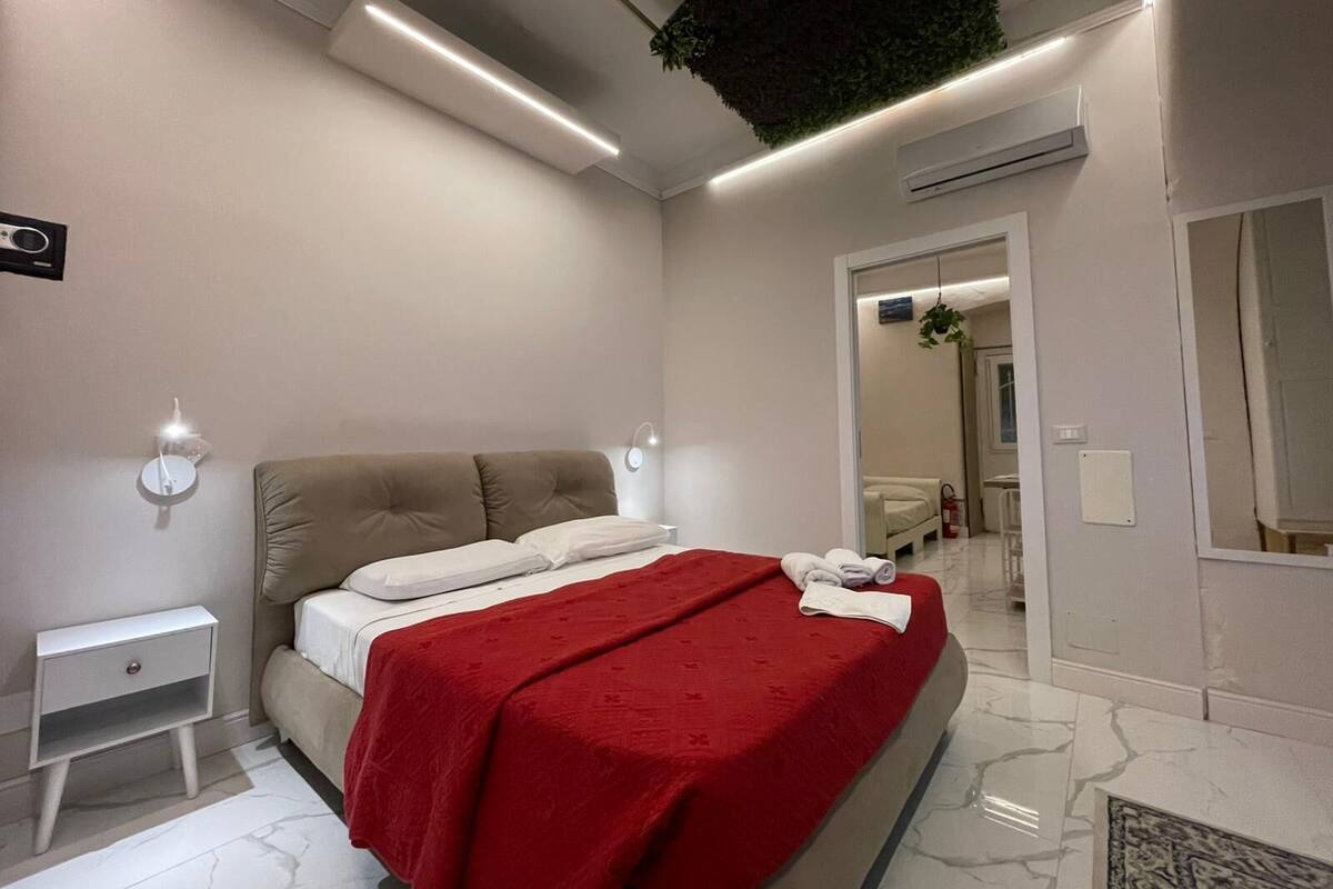 A modern bedroom with a bed, bedside table, and a red throw blanket.