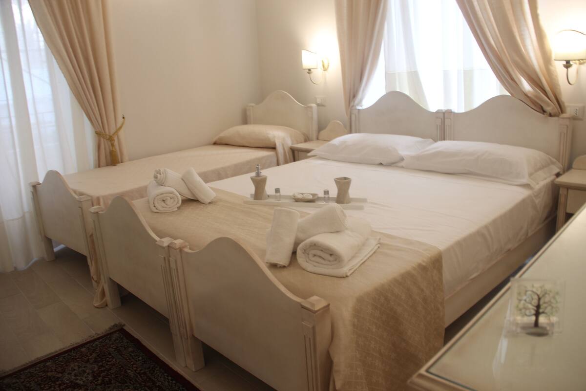 A hotel room with two beds, a small table with a tray of amenities, and a nightstand with a lamp.