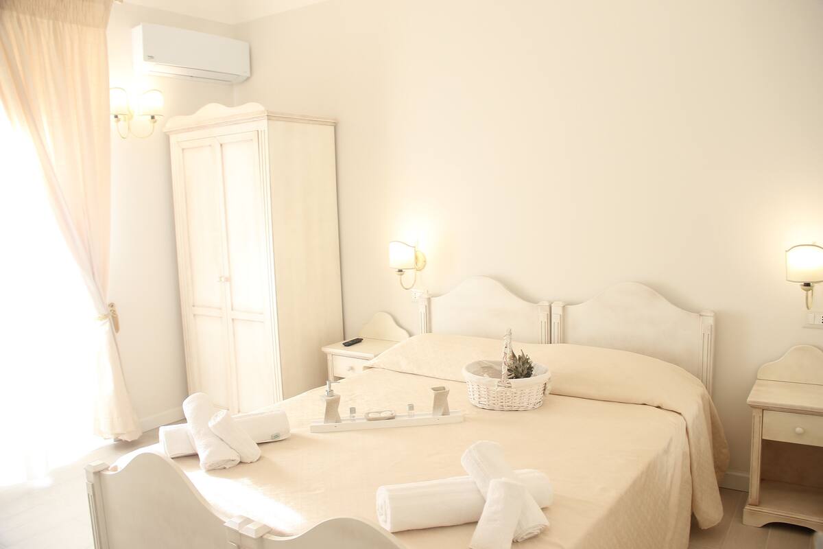 A hotel room with a bed, bedside tables, a wardrobe, and a window with curtains.