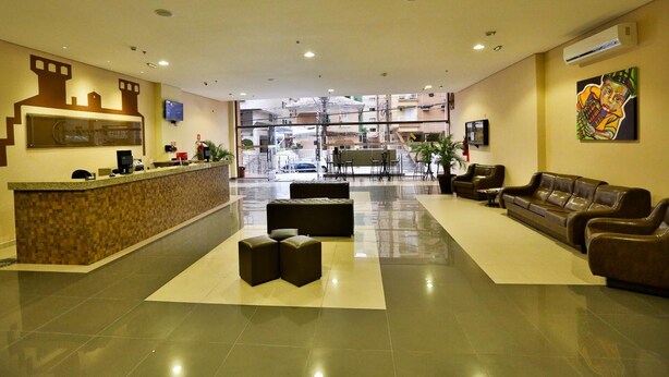 A hotel lobby with a reception desk, seating area, and a large window offering a view of the street.