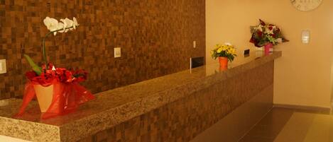 Un área de recepción con una pared de madera, un reloj y un mostrador con flores.