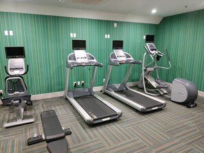 A fitness room with treadmills, a stationary bike, and a rowing machine.