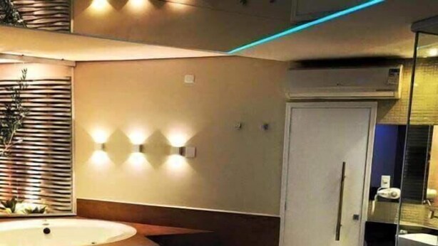 Un dormitorio moderno con una cama grande, una bañera redonda y un box de ducha de cristal.