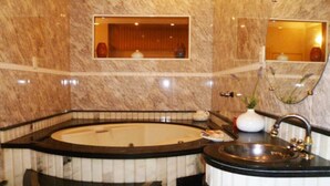 Un baño con una bañera grande, un lavamanos y un espejo.