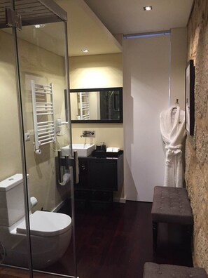 A modern bathroom with a glass shower enclosure, a white toilet, a sink, and a bathtub.