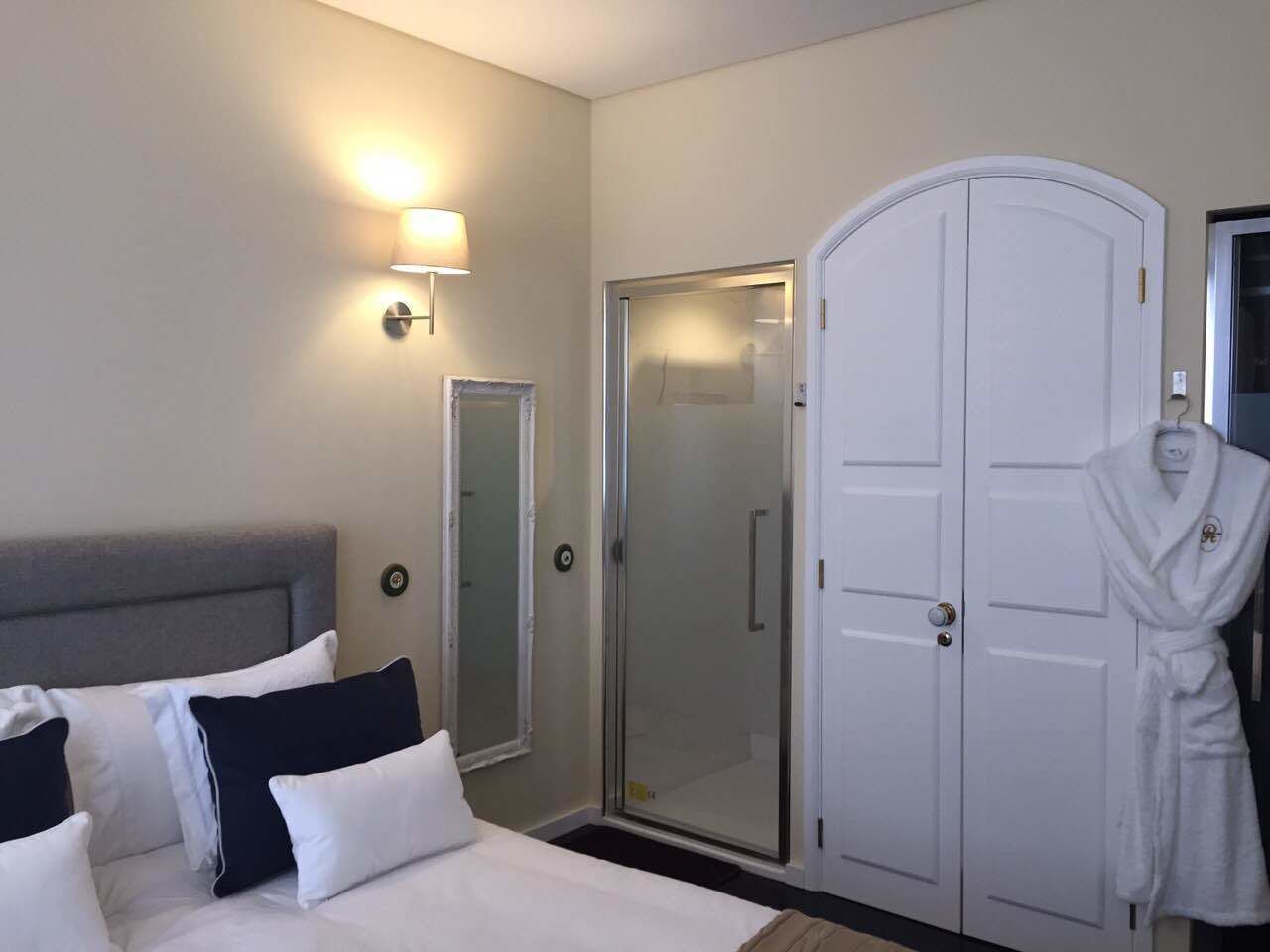 Ein Hotelzimmer mit Bett, Kleiderschrank, Dusche und Bademantel, der an der Tür hängt.