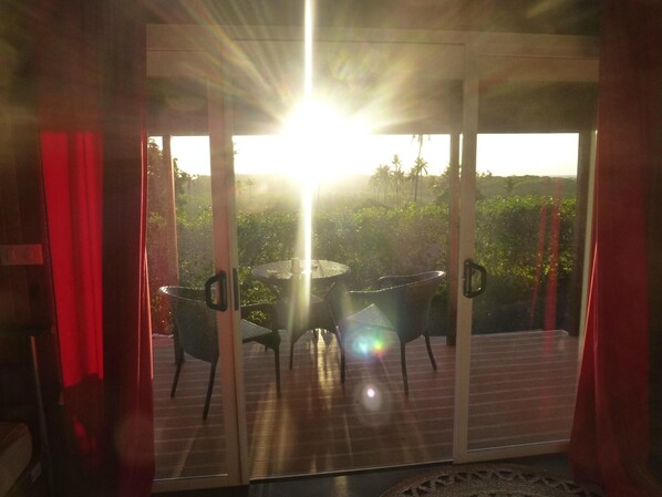 A room with a sliding glass door leading to an outdoor area with a table and chairs. - Pension La Perruche Rouge (Rimatara Island)
