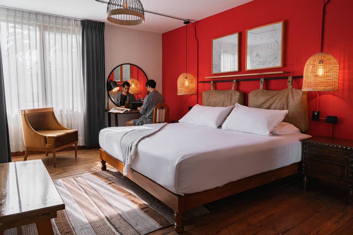 Una habitación de hotel con una cama grande, muebles de madera y obras de arte en las paredes.