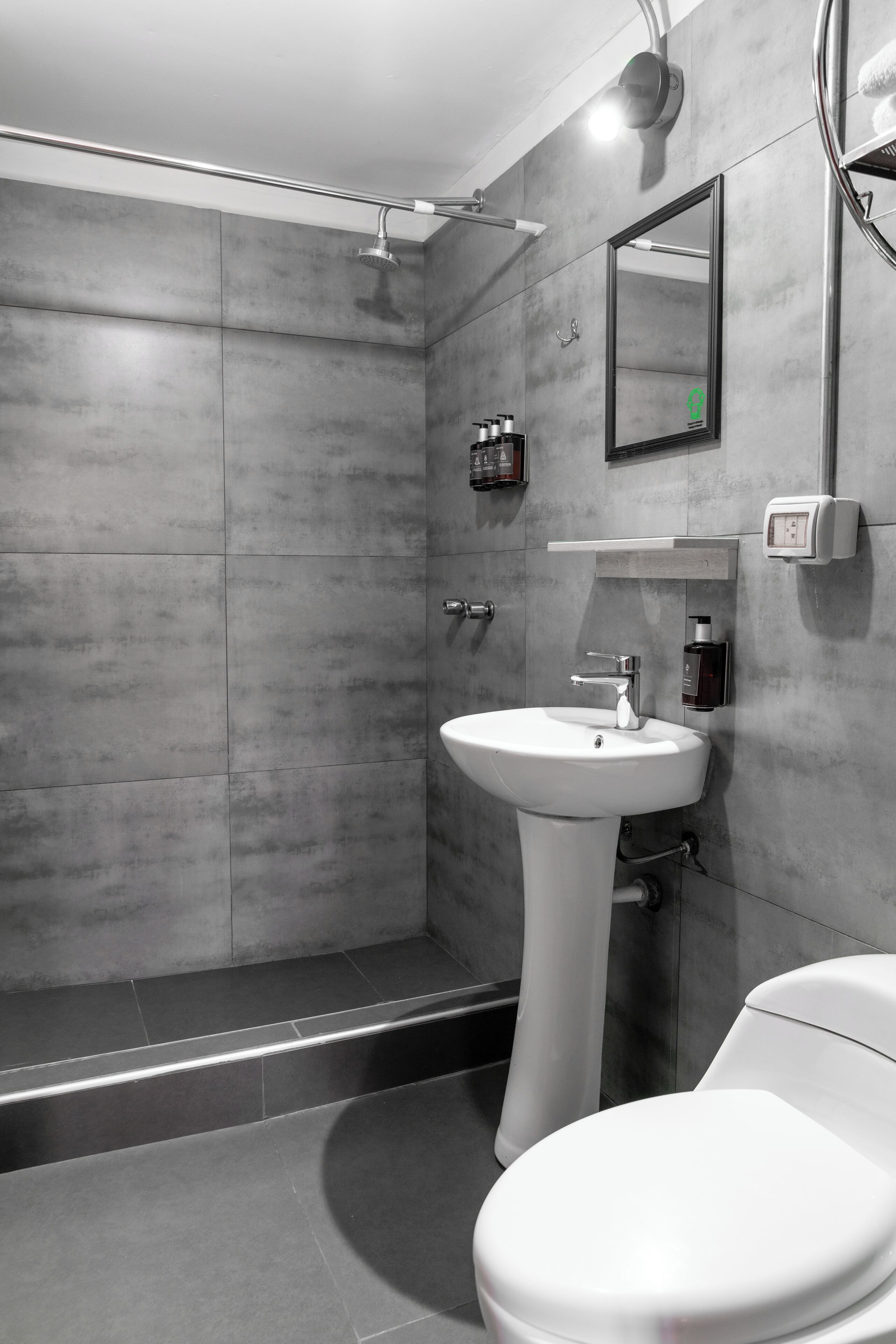 A modern bathroom with a walk-in shower, a pedestal sink, and a toilet.