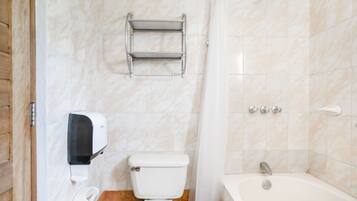Un baño con inodoro, secamanos, dispensador de toallas, ducha y bañera.