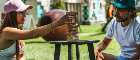 Deux personnes jouent au Jenga sur une petite table, à l’extérieur.