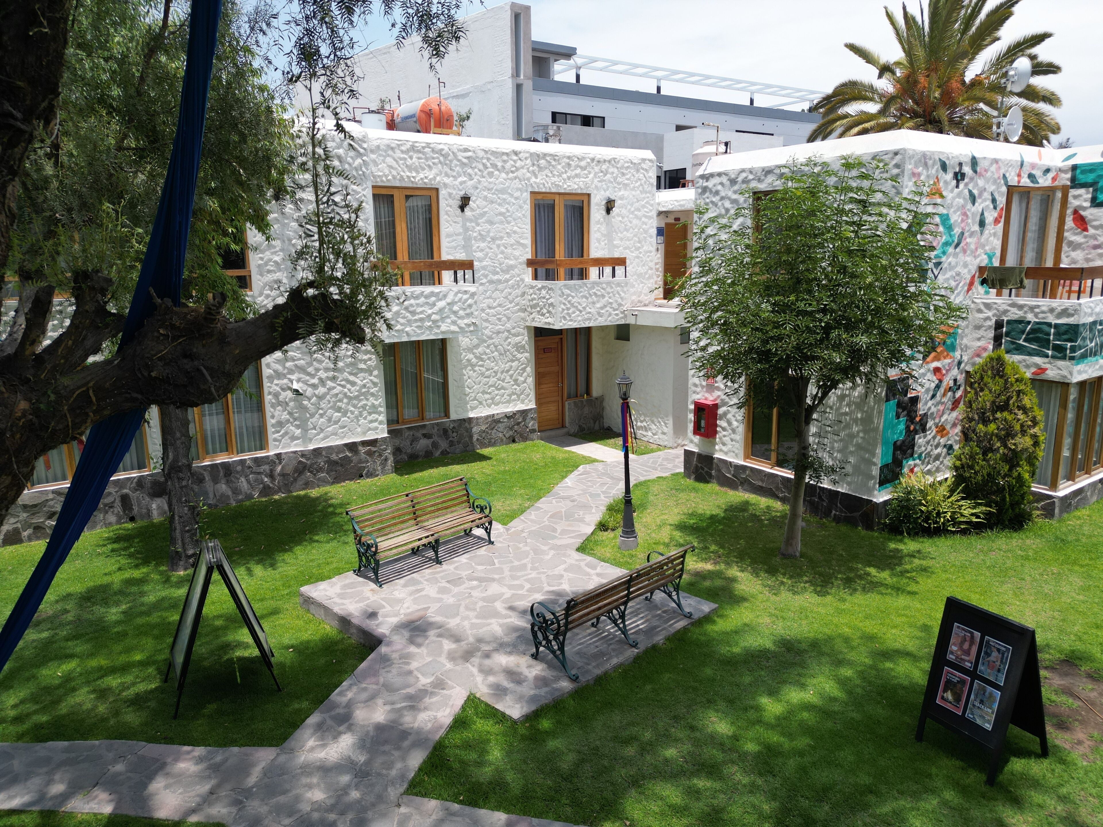 Un patio con dos bancos, un letrero pequeño y un árbol.