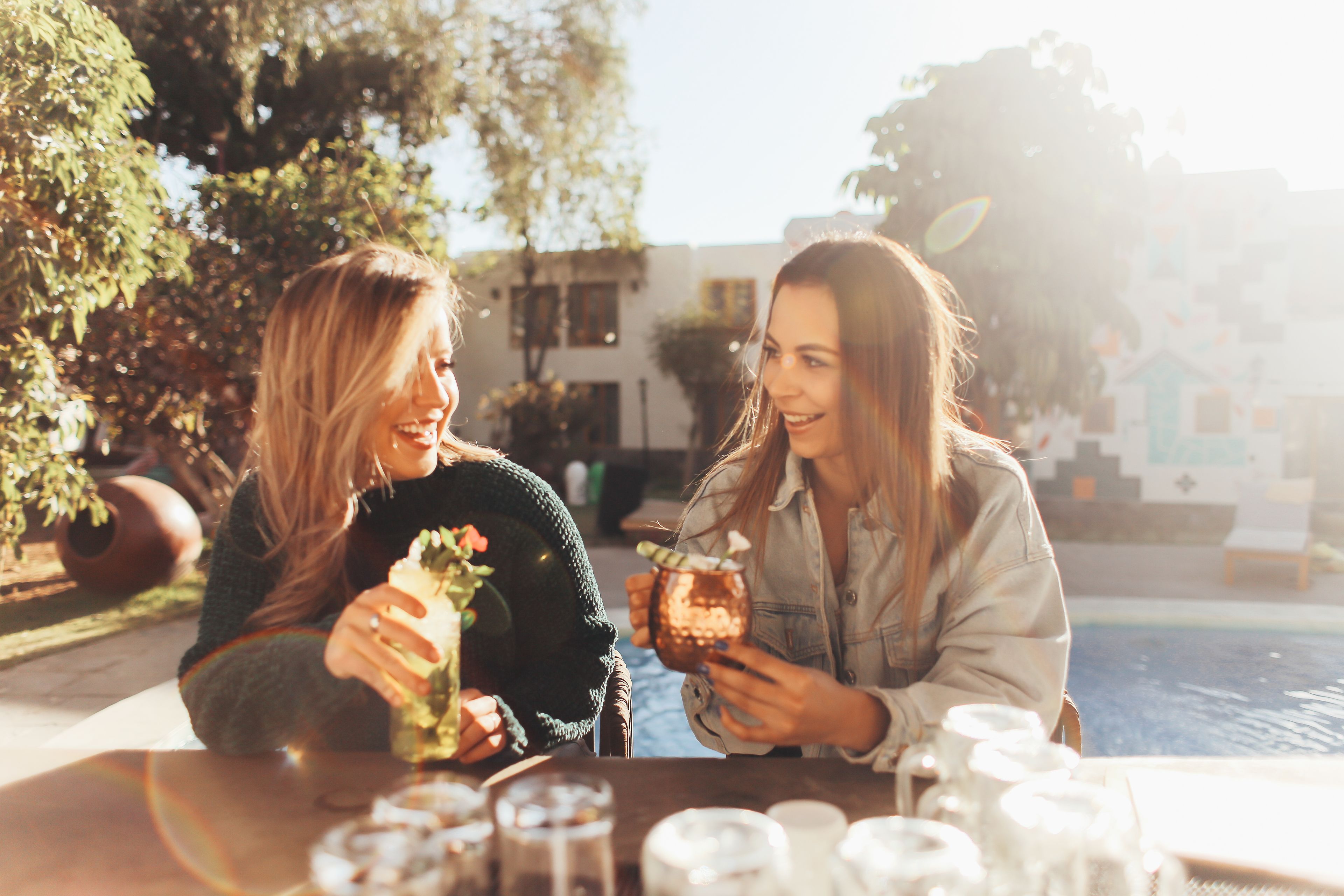 Dos personas sentadas en una mesa al aire libre, con una piscina al fondo.