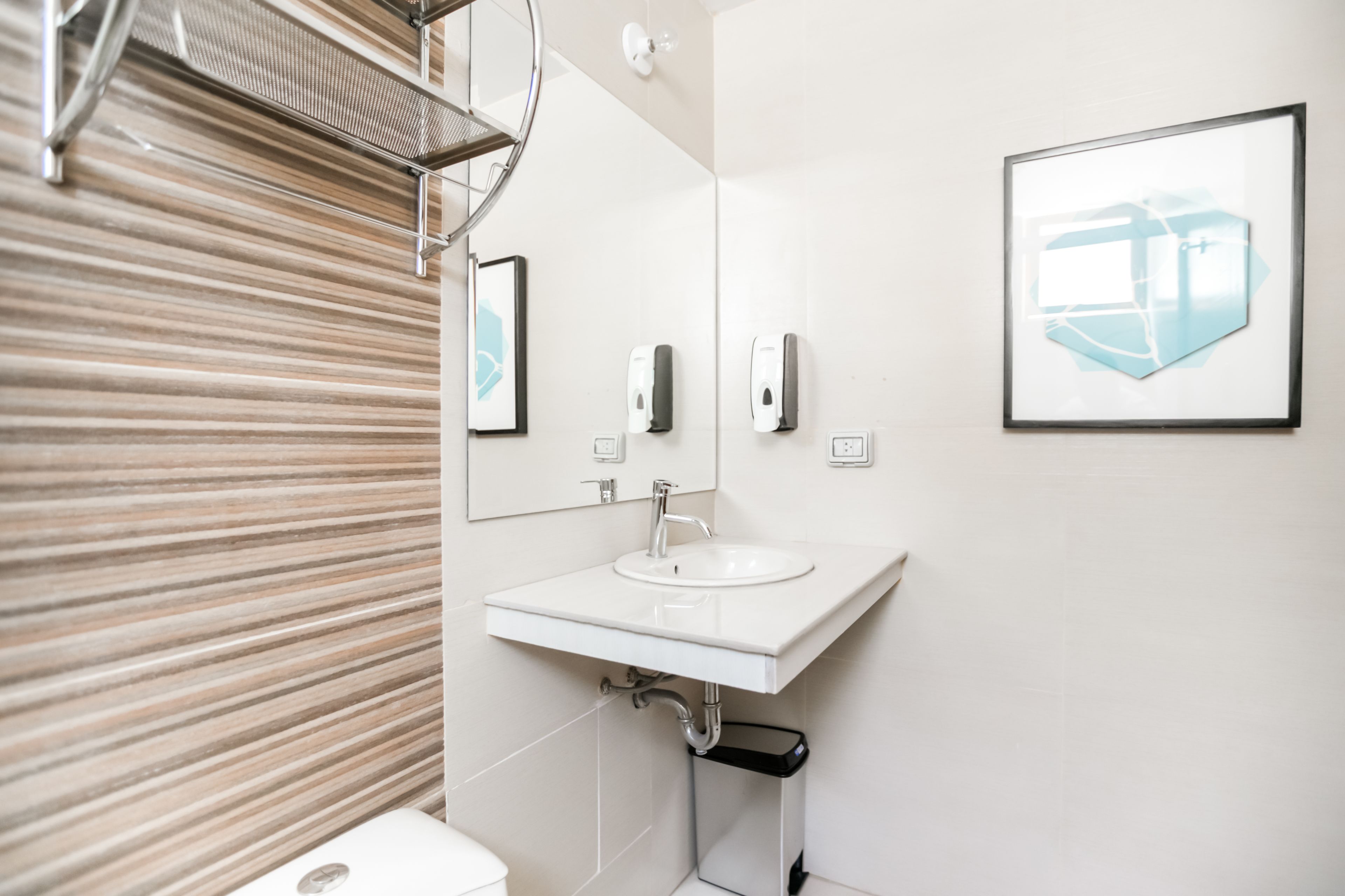 Un baño moderno con lavamanos blanco, un espejo y un inodoro.