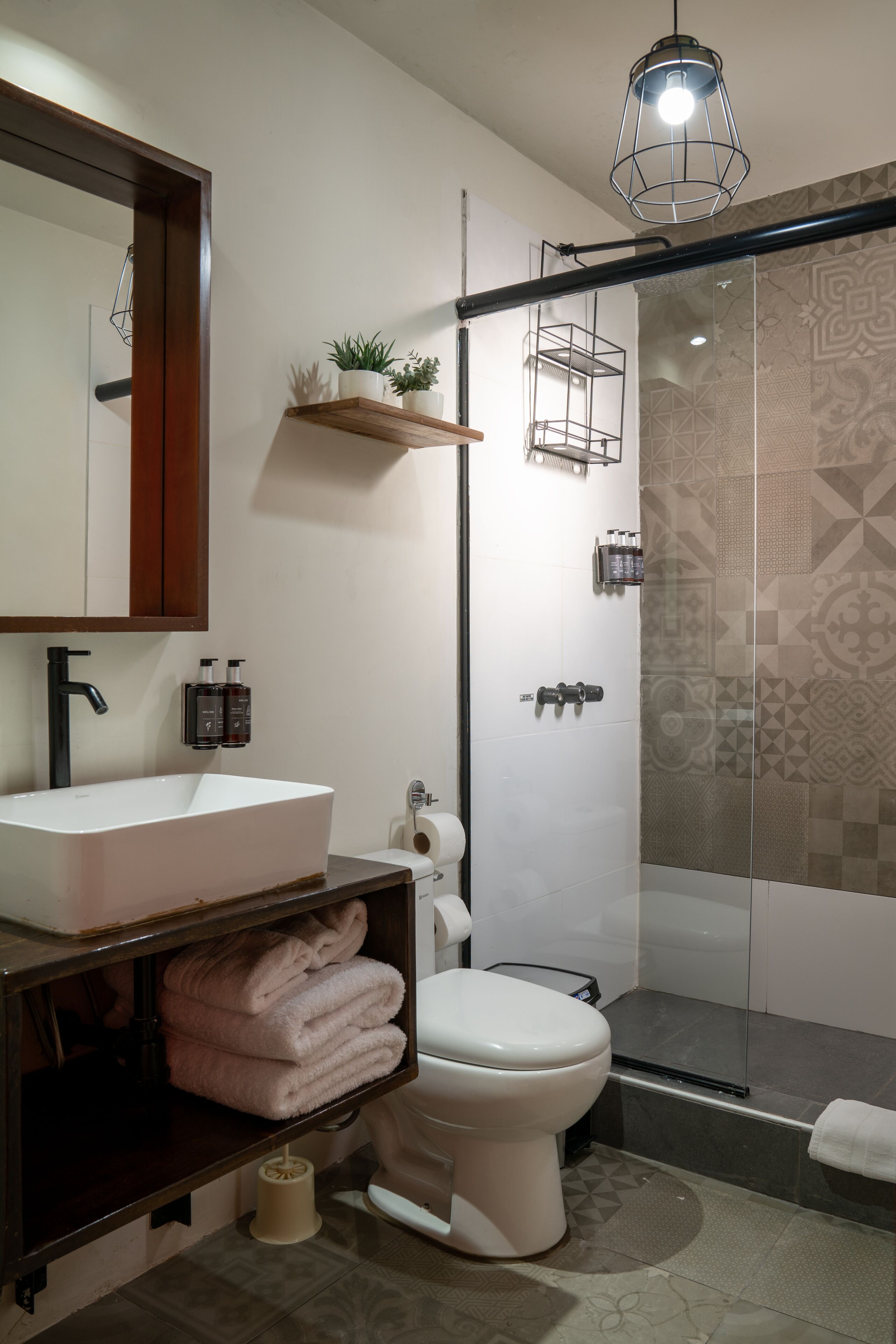 Un baño moderno con un lavabo grande, un inodoro, una cabina de ducha con paredes de vidrio y un perchero para toallas.