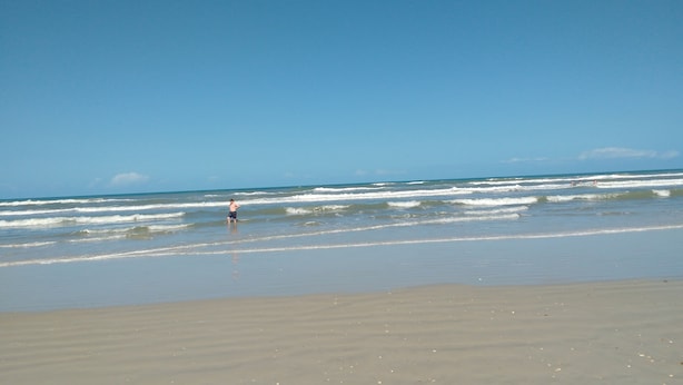 Ein Strand mit Wellen und blauem Himmel.