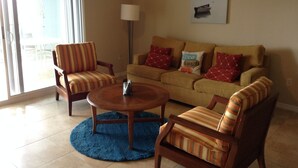 Ein Wohnzimmer mit einer Couch, zwei gestreiften Sesseln, einem Couchtisch und einer Lampe.