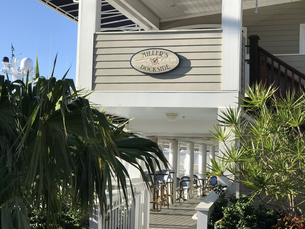 A building with a sign reading "Miller's Doc'side" and outdoor seating with chairs and tables.