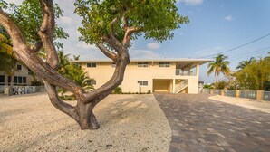 A two-story building with a paved driveway and a tree in the foreground. - Salty Anglers: Waterfront Heated Pool, Dock & Walk to Sombrero Beach in Marathon (Marathon)