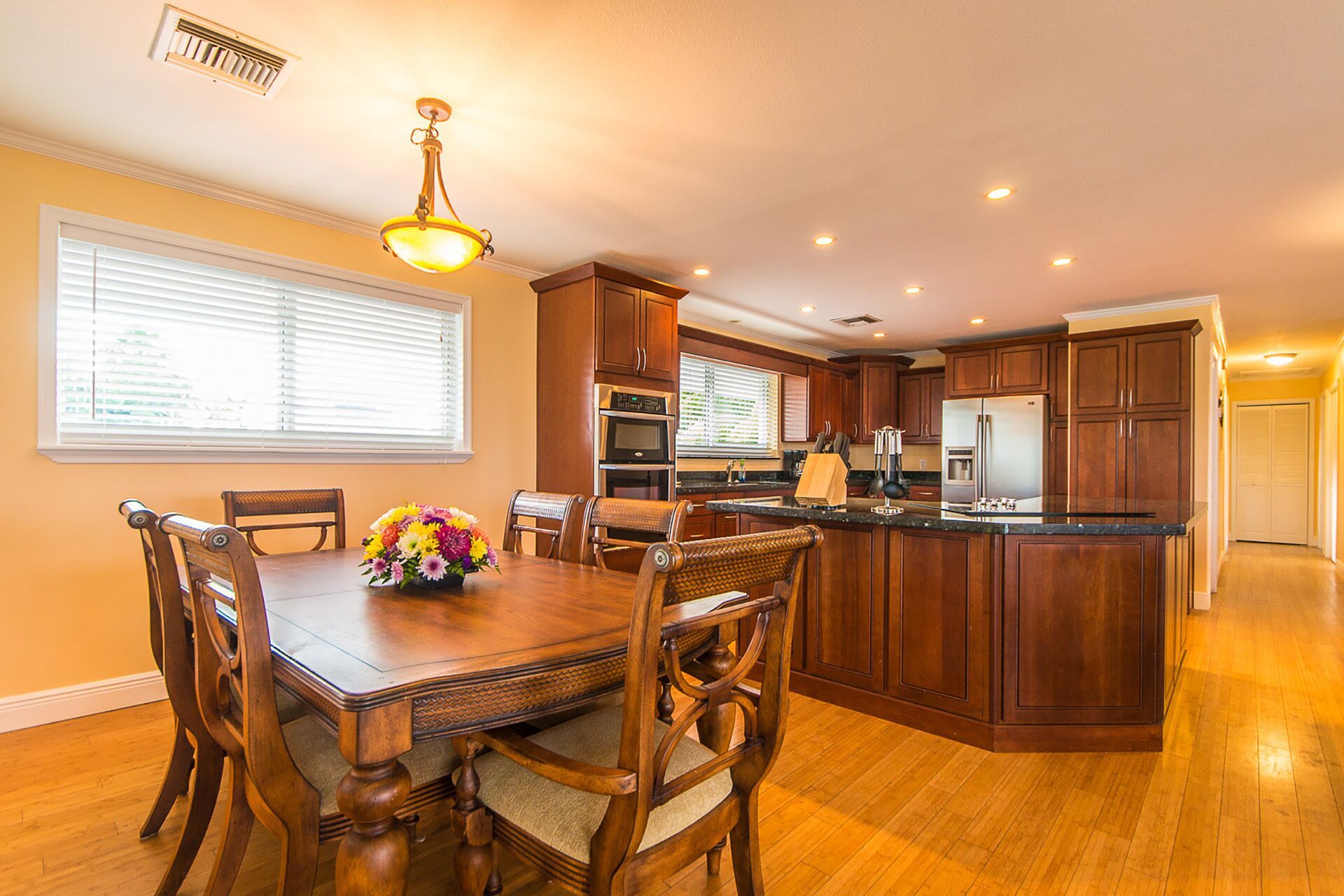 A spacious kitchen with wooden cabinets, a central island, and a dining area with a wooden table and chairs.