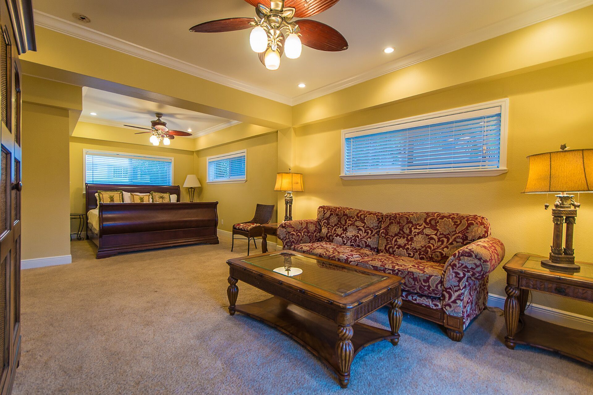 A living room with a sofa, a coffee table, a lamp, and a ceiling fan.