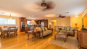 A spacious living room with hardwood flooring, a dining area with wooden furniture, a kitchen with modern appliances, and a ceiling fan. - Salty Anglers: Waterfront Heated Pool, Dock & Walk to Sombrero Beach in Marathon (Marathon)