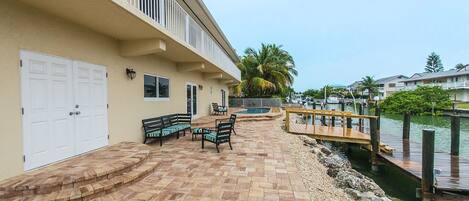 A waterfront patio with a wooden deck, outdoor seating, and a view of the marina.