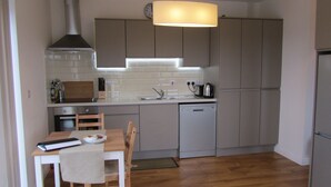 A compact kitchen with a dining area, featuring a dishwasher, a stove, and a sink. - Atlantic Apartment. Wonderful views of the Wild Atlantic Ocean and mountains (Renvyle)