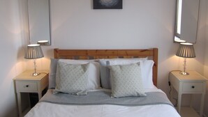 A neatly made bed with two pillows, a wooden headboard, and two bedside tables with lamps. - Atlantic Apartment. Wonderful views of the Wild Atlantic Ocean and mountains (Renvyle)