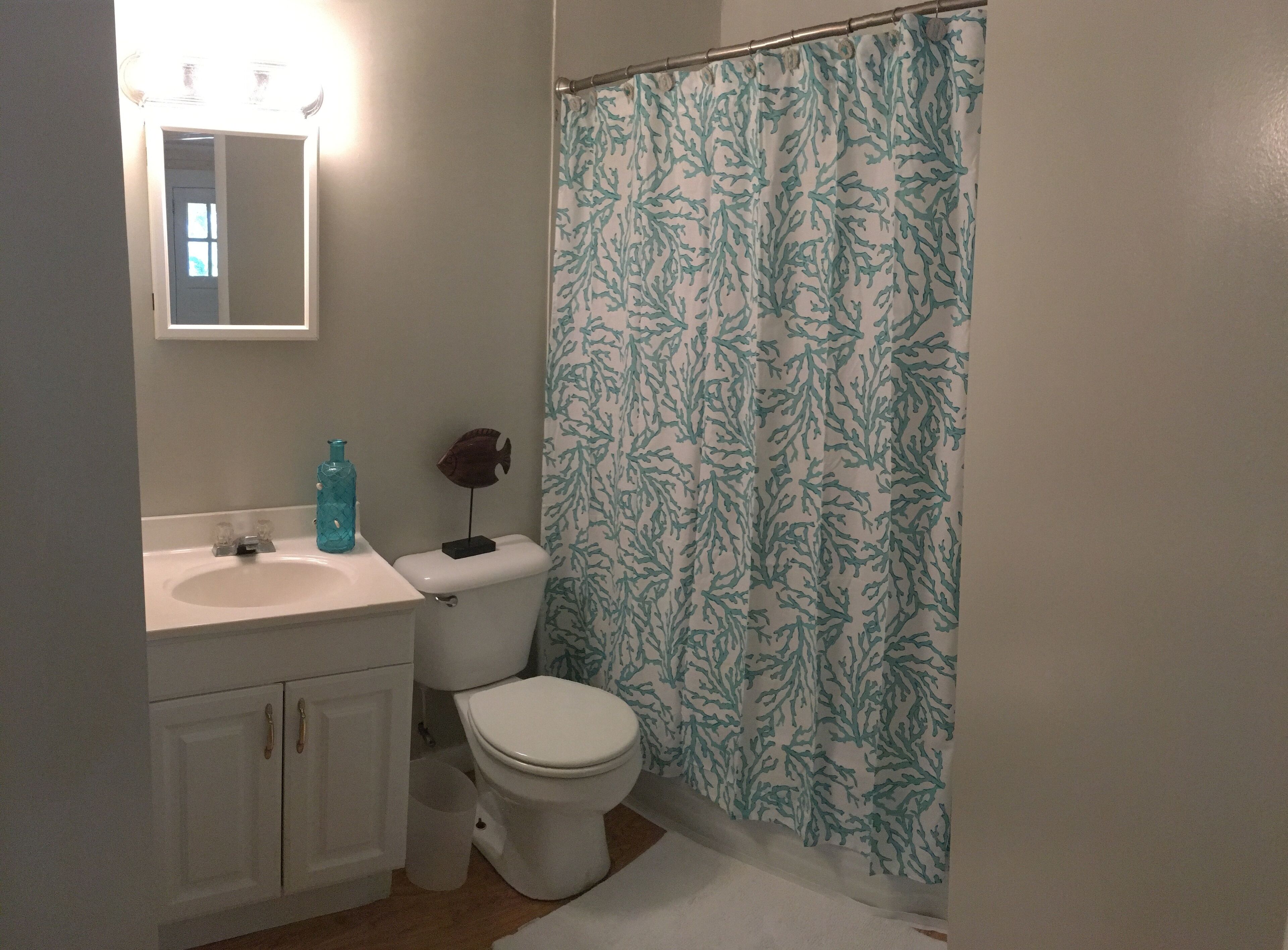 A bathroom with a toilet, sink, and shower curtain.