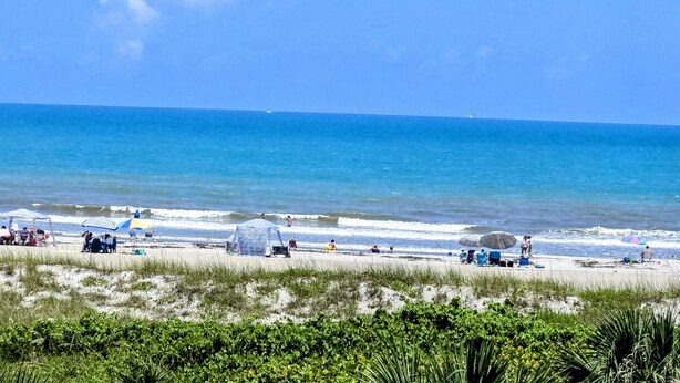A beach with people, umbrellas, and beach chairs. - OCEAN FRONT Classy, Beachy Double Balcony Condo #306 at Cape Winds Resort (Cape Canaveral)