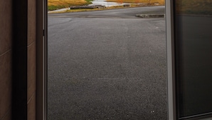 A view through a glass door of a parking area with a distant landscape, including mountains and a river. - Family - friendly    (Akranes)