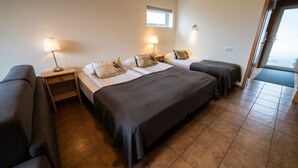 A hotel room with two beds, a sofa, a window, and a door. - Family - friendly    (Akranes)