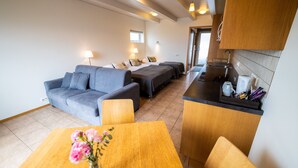 A compact living space with a sofa, two single beds, a dining table, and a kitchenette. - Family - friendly    (Akranes)