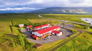 An aerial view of a building complex with multiple structures, a parking area, and a road curving through the landscape. - Family - friendly    (Akranes)