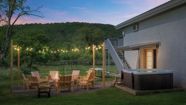 A hot tub, outdoor seating, and a staircase leading to a covered area.