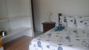 Une chambre à coucher comprenant un lit, une table de chevet, une lampe et une étagère.