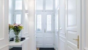 A hallway with white doors, a mirror, a chandelier, and a vase with flowers. - Chic flat by the Great Market Hall (Budapest)