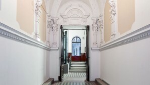 A hallway with ornate white ceiling and walls, leading to a staircase. - Chic flat by the Great Market Hall (Budapest)