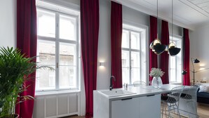 A modern kitchen with a central island, red curtains, and pendant lighting. - Chic flat by the Great Market Hall (Budapest)