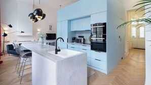 A modern kitchen with a central island, built-in appliances, and a dining area with bar stools. - Chic flat by the Great Market Hall (Budapest)