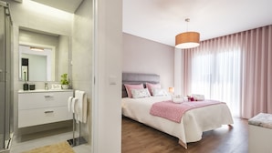 Un dormitorio moderno con una cama grande, mesitas de noche, un tocador con espejo y una zona de ducha.